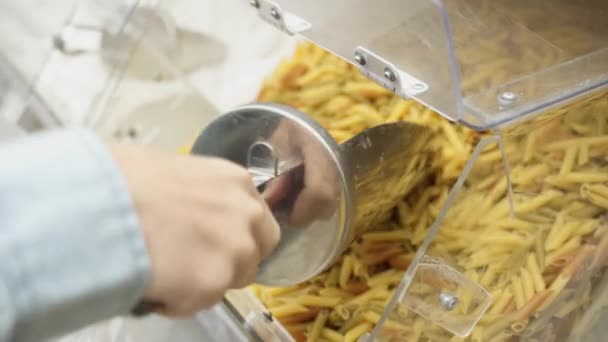 Buyer picks up pasta in store using scoop - Imágenes, Vídeo