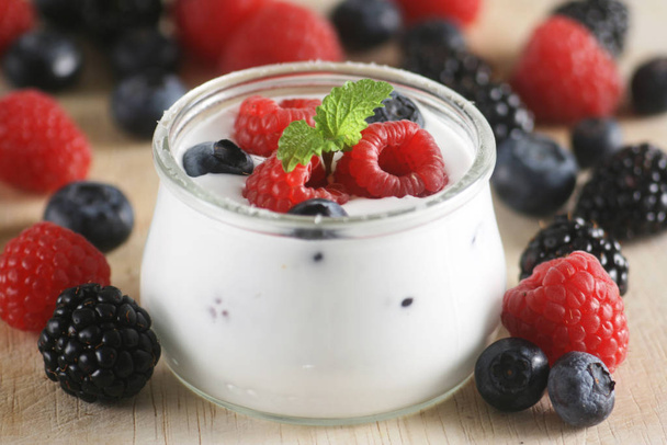 крупним планом шматок йогурту в банці зі свіжими ягодами
 - Фото, зображення