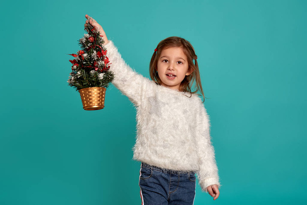 Vrolijk kerstfeest en fijne feestdagen. Schattig klein meisje met een kerstboom. Kerstvakantie concept. - Foto, afbeelding