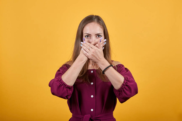 Νεαρή κοπέλα κρύβει το στόμα της με τα χέρια της - Φωτογραφία, εικόνα