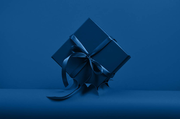 Blue gift box with bow on classic blue paper backround - Foto, Imagem