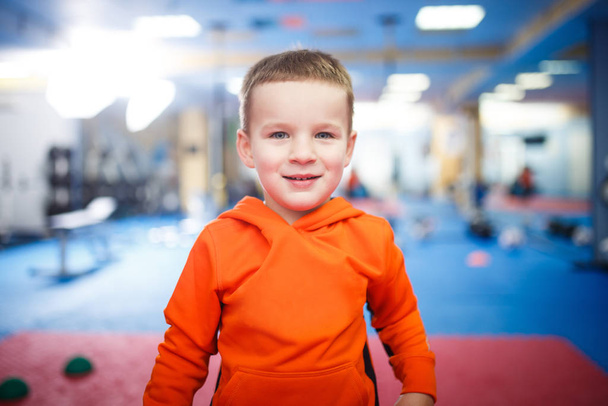 Portrait d'un enfant posant dans la salle de gym. Le thème est le développement physique des enfants. Un sportif en tenue de sport regarde la caméra. Enfance et santé
 - Photo, image