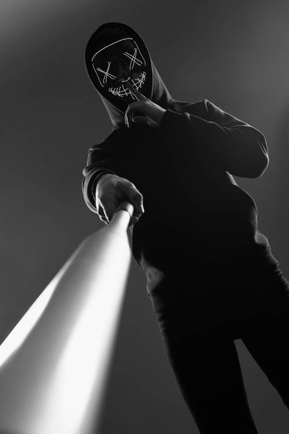 Anonieme crimineel met honkbalknuppel in een zwarte hoodie en n - Foto, afbeelding