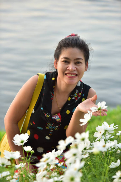 portrait de jeune femme asiatique posant dans un parc floral avec des fleurs colorées le jour
   - Photo, image