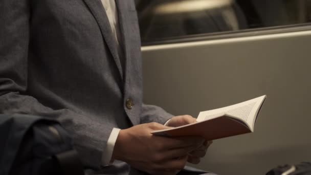 Close up shot of businessman in suit reading book in subway train on the way home - Πλάνα, βίντεο