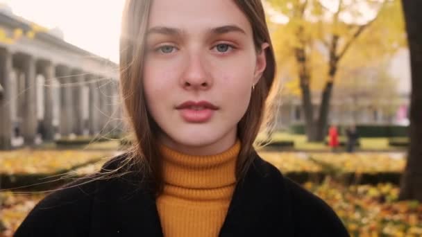 Portrait de fille décontractée attrayante posant avec soin sur la caméra dans le parc de la ville au coucher du soleil
 - Séquence, vidéo