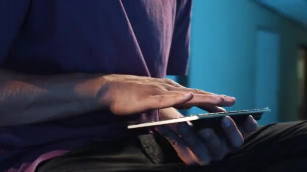 Homem de t-shirt está sentado no quarto escuro, limpando teclado portátil com os dedos
 - Filmagem, Vídeo