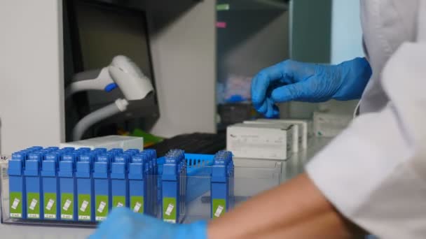 Travailleur de laboratoire moderne place des échantillons de sang sur rack, fermer. Spécialiste effectue des tests sanguins et ADN sur un dispositif spécial. Tourné en 4k
 - Séquence, vidéo
