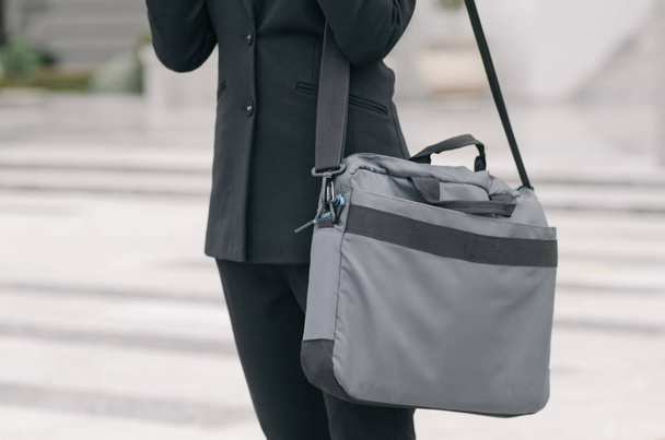 niezidentyfikowana młoda bizneswoman wykonawcza w czarnym garniturze stoi z torbą procy - Zdjęcie, obraz