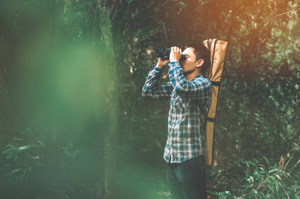 Man with binoculars telescope in forest looking destination as l - Valokuva, kuva