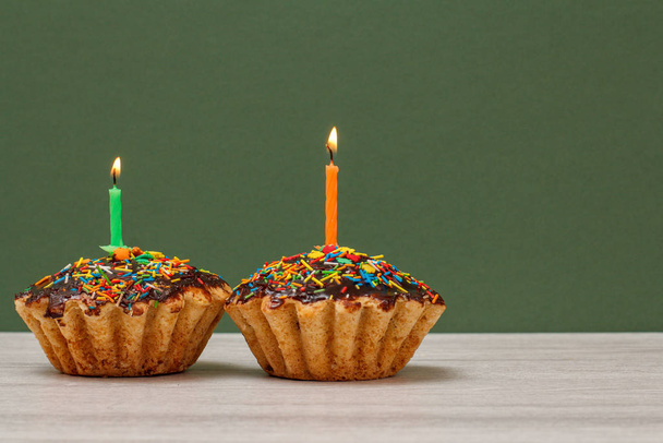cupcakes d'anniversaire avec des bougies festives brûlantes sur fond vert
. - Photo, image