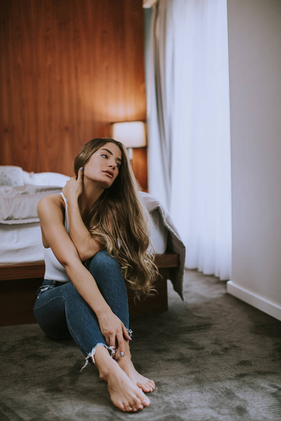 Attraente giovane donna seduta sul pavimento in camera da letto presso l'appartamento
 - Foto, immagini