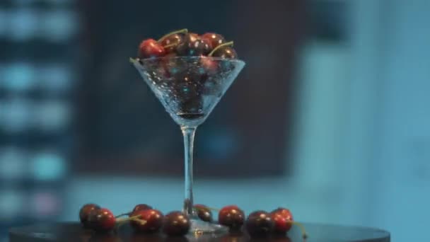 Isolated coctail glass full of dark-red berries, placed on black round table. - Felvétel, videó