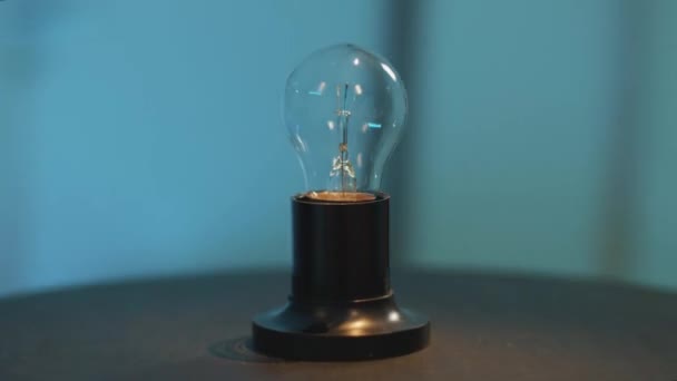 Camera draait dynamisch rond een lamp licht geplaatst op donkere ronde tafel - Video