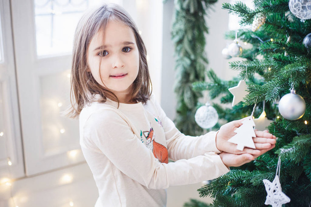 Κοριτσάκι με διακόσμηση για χριστουγεννιάτικο δέντρο, χριστουγεννιάτικο εσωτερικό, προετοιμασία για τα Χριστούγεννα και το νέο έτος, διακόσμηση σπιτιού - Φωτογραφία, εικόνα