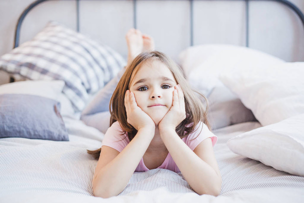 Girl lying on the bed, little girl resting among the pillows and blankets, dreams - Foto, Bild