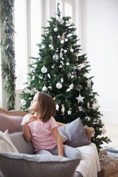Girl near the Christmas tree, waiting for Santa Claus and a miracle - Foto, immagini