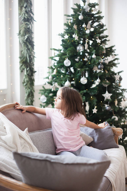 Girl near the Christmas tree, waiting for Santa Claus and a miracle - Valokuva, kuva