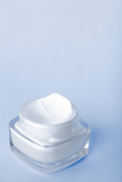 Gezicht crème moisturizer pot op blauwe achtergrond, hydraterende huid - Foto, afbeelding