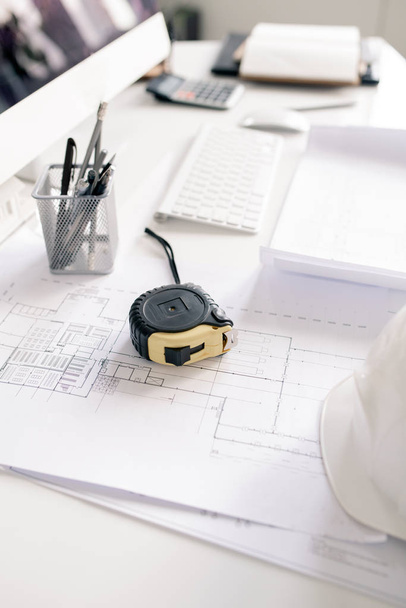 Measuring tape, pencils and blueprints with sketches on workplace of contemporary engineer in office - Fotoğraf, Görsel