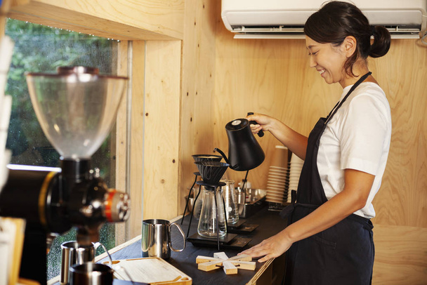 Donna giapponese che indossa grembiule in piedi in un Eco Cafe, preparare il caffè
. - Foto, immagini