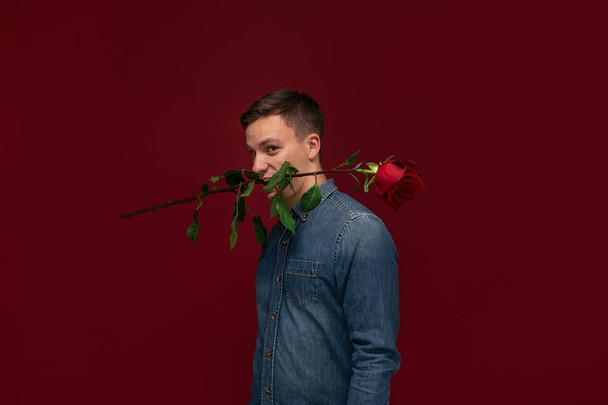 Молодий красивий чоловік тримає одну червону троянду, щоб подарувати своїй коханій. Бути романтичним
 - Фото, зображення