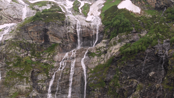 Aerial view drone footage several waterfalls flowing down steep large rocks high in the mountains surrounded by lush greenery and not melted snow. The concept of nature reserves of the North Caucasus - Footage, Video