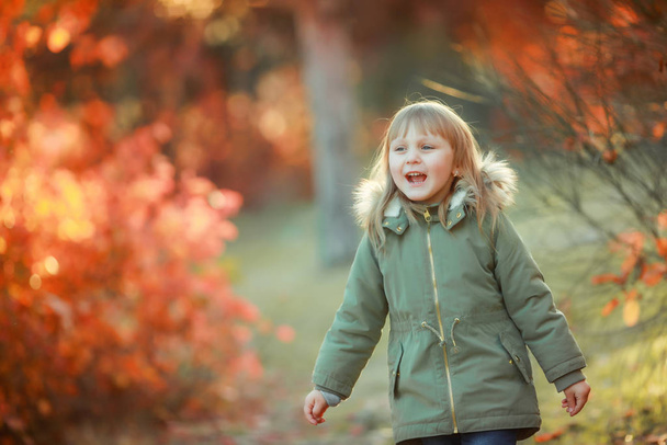 Menina feliz com cabelos brancos em uma jaqueta quente andando perto das árvores e respirar ar limpo
 - Foto, Imagem