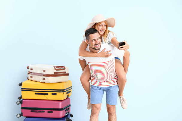 Koppel met koffers selfie op kleur achtergrond - Foto, afbeelding