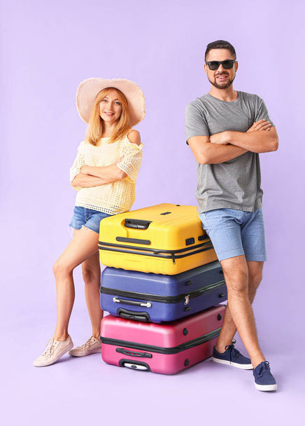 Couple with suitcases on color background - Фото, изображение