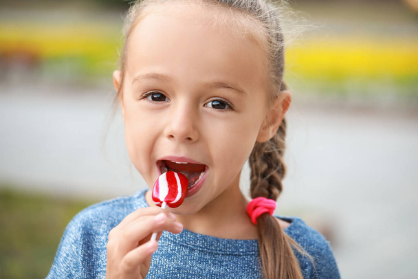 Cute little girl with sweet lollipop outdoors - Photo, Image