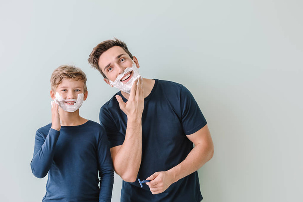 Pai com filho aplicando espuma de barbear em seus rostos contra fundo cinza
 - Foto, Imagem