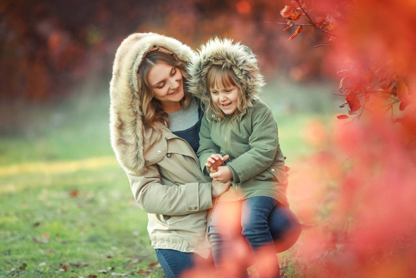 Autumn mother and daughter on a walk in the garden outdoors - Foto, imagen