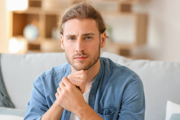 Handsome man sitting on sofa at home - Photo, Image