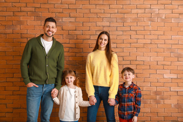 レンガの壁の近くの冬服の幸せな家族 - 写真・画像
