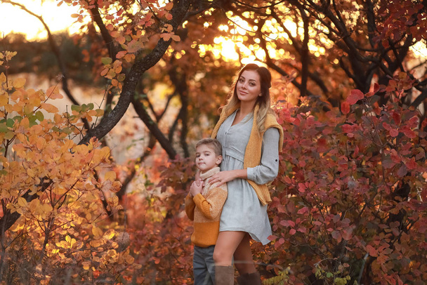Mutter und Sohn spazieren im Herbst gemeinsam in warmer Kleidung durch den Park - Foto, Bild