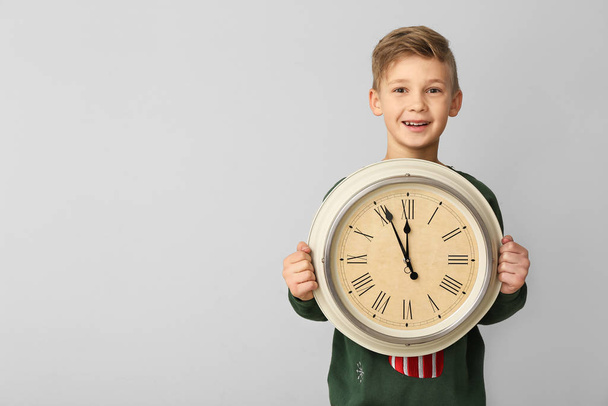Маленький хлопчик з годинником на світлому фоні. Концепція зворотного відліку Різдва
 - Фото, зображення