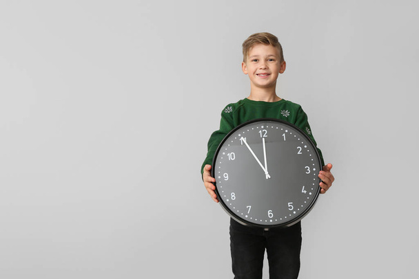 Little boy with clock on light background. Christmas countdown concept - Photo, Image