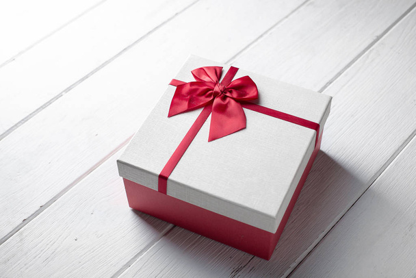 Cadeau actuel boîte avec ruban rouge sur bois blanc texturé avec C
 - Photo, image
