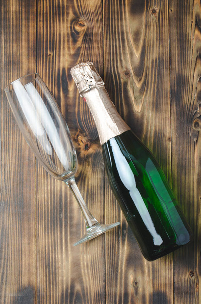 Bottle of sparkling wine and a glass on a wooden background. Top - Fotó, kép