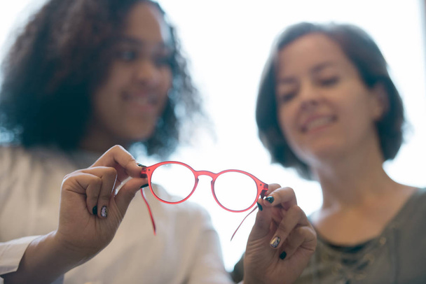Coppia di nuovi occhiali in mano di giovane ottico clinico dando raccomandazioni a cliente femminile
 - Foto, immagini