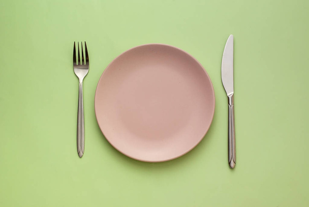 Порожня рожева тарілка з посудом на зеленому
 - Фото, зображення