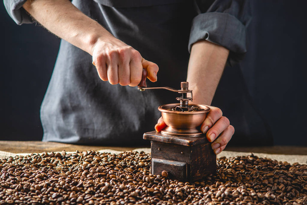 Koyu önlüklü baristalar el yapımı kahve çekirdeklerinin üzerinde öğütülüyor. Espresso için taze kahve. - Fotoğraf, Görsel