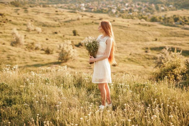 Adolescente com flores descansando no campo
 - Foto, Imagem