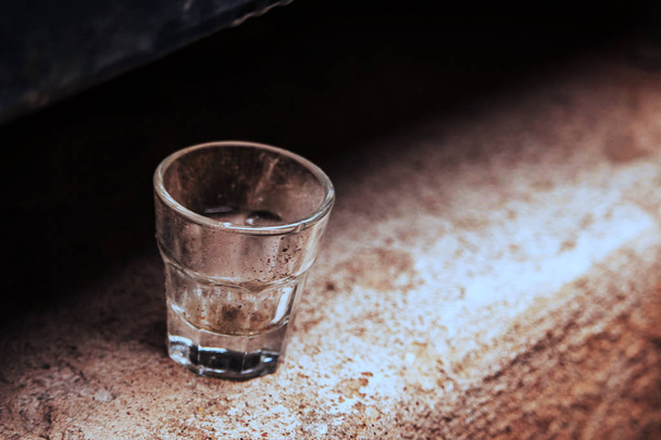 Small empty glass standing alone on concrete surface - Fotoğraf, Görsel