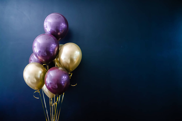 Набор золотых и фиолетовых шариков на темном фоне. Концепция праздника, открытка
 - Фото, изображение