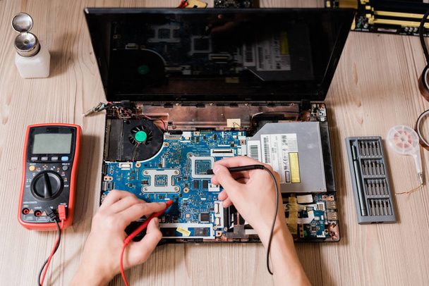 Hands of contemporary technical repairman using two small soldering-irons to repair broken laptop - Φωτογραφία, εικόνα