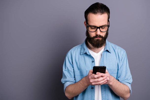 Portrait of concentrated freelancer blogger man use smart phone read social media information chat with clients colleagues wear good look jeans outfit isolated over grey color background - Foto, Imagem