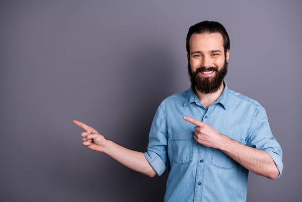 Portrait of positive cheerful confident guy promoter point index finger copy space demonstrate adverts present promotion wear good look outfit isolated over grey color background - Foto, imagen