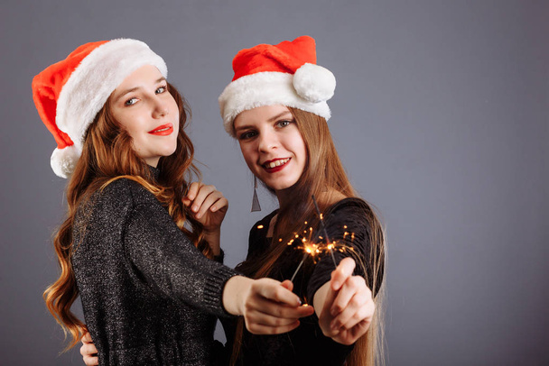 Atrakcyjne wesołe dziewczyny z kręconymi długimi włosami w świątecznych kapeluszach - Zdjęcie, obraz